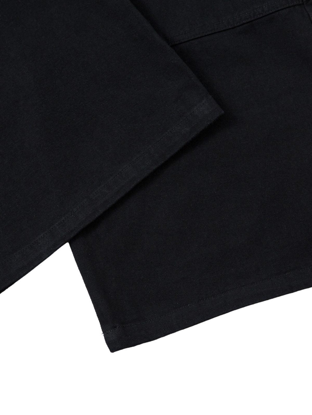 A close-up of TALISHKO's deconstructed cargo jeans, focusing on the sleek black fabric.
