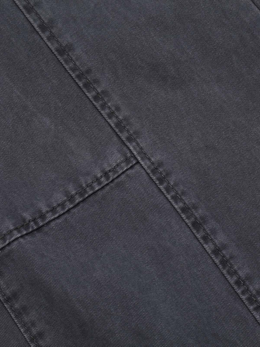 Intricate look at TALISHKO's deconstructed jeans, highlighting unique stitching and dark fabric.