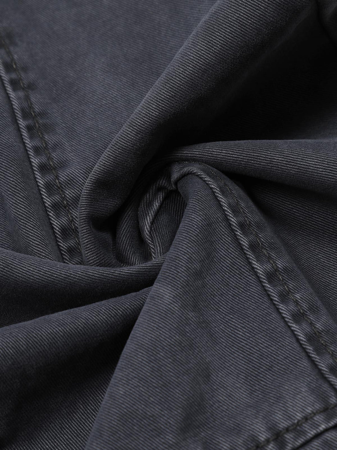 Detailed fabric and stitching of TALISHKO deconstructed jeans, showcasing dark denim texture.