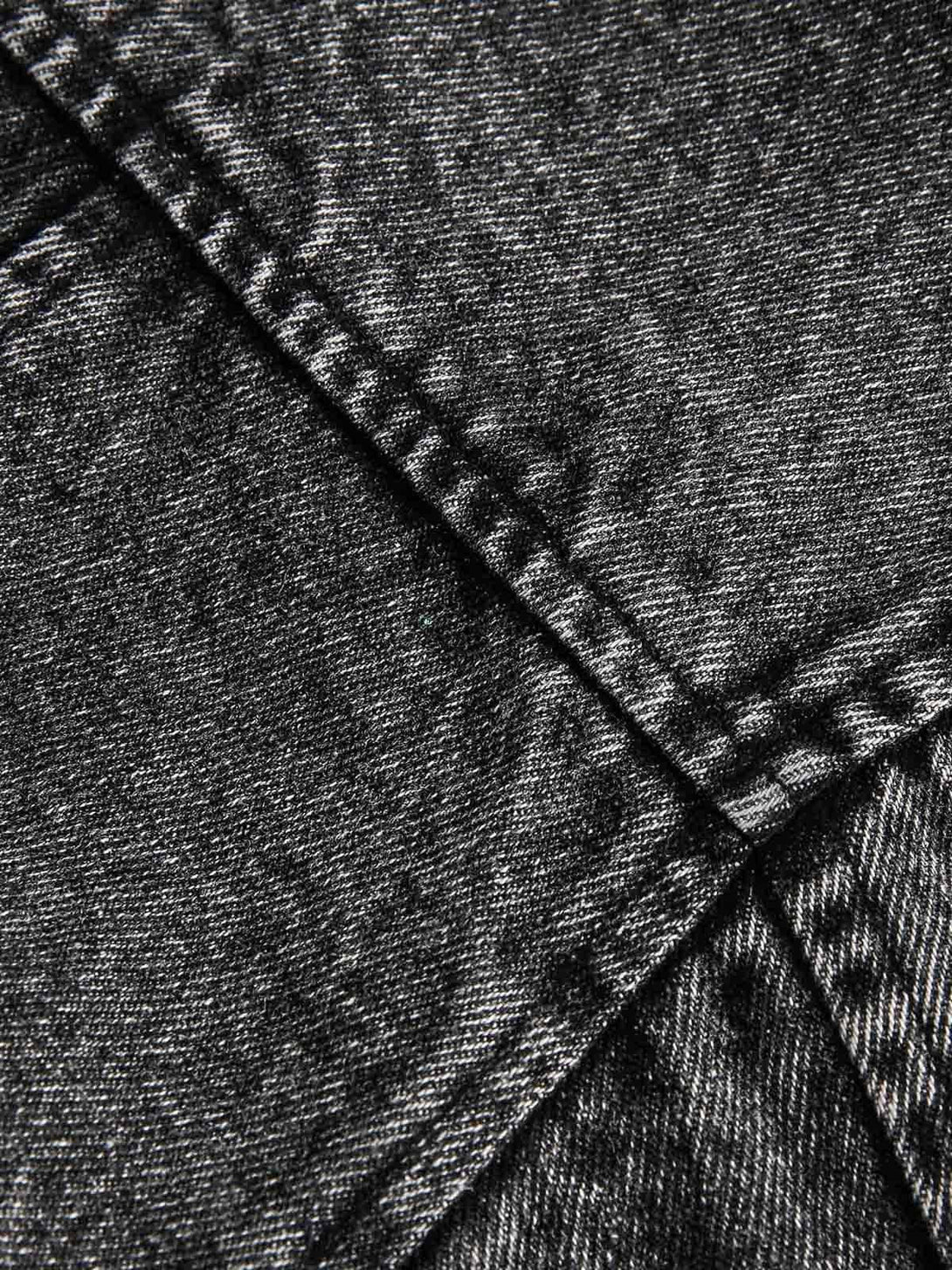 Zoomed-in texture of TALISHKO's deconstructed denim jacket, highlighting detailed stitching.