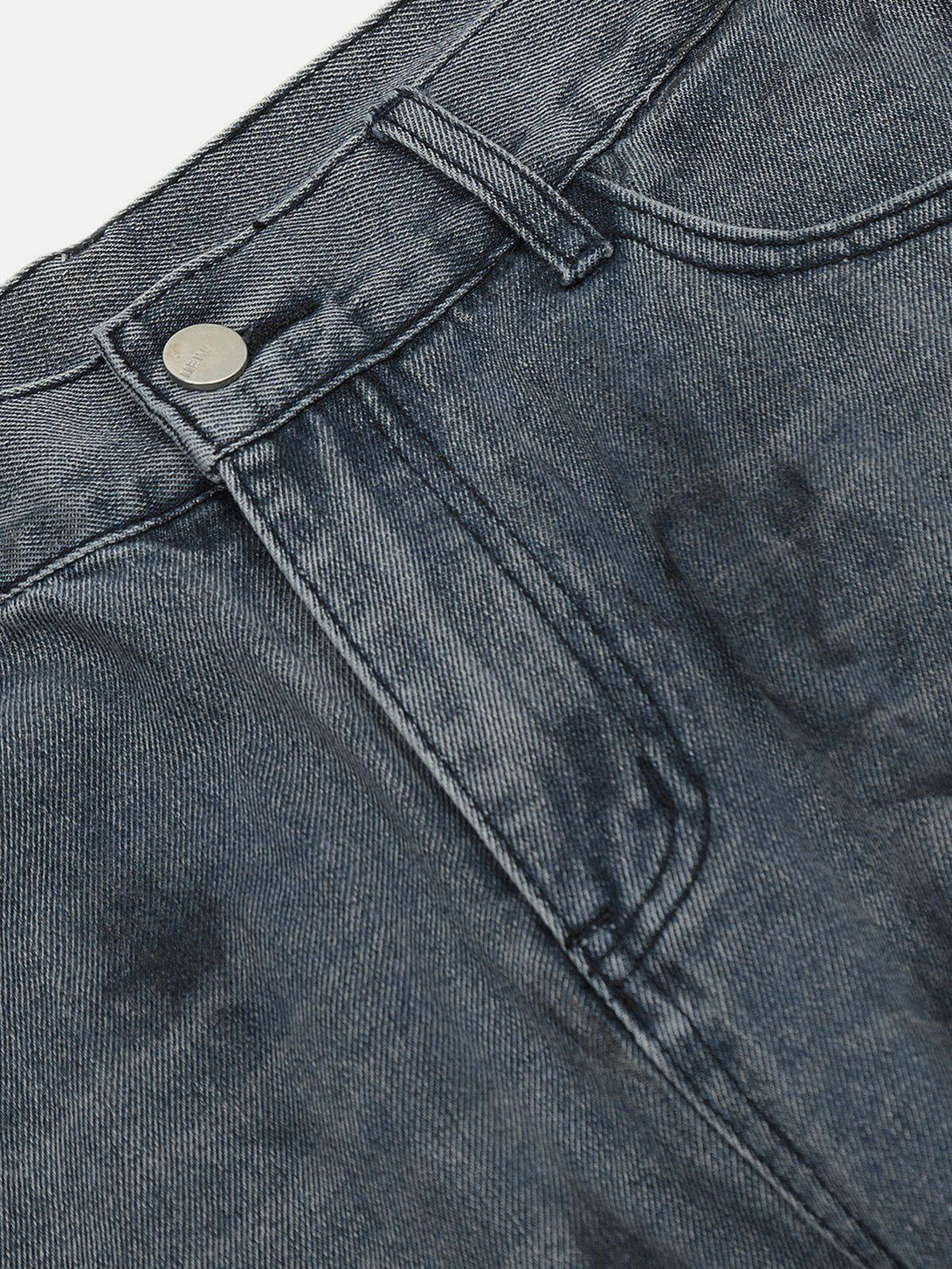 A close-up of TALISHKO's deconstructive design washed jeans, highlighting unique texture and button.