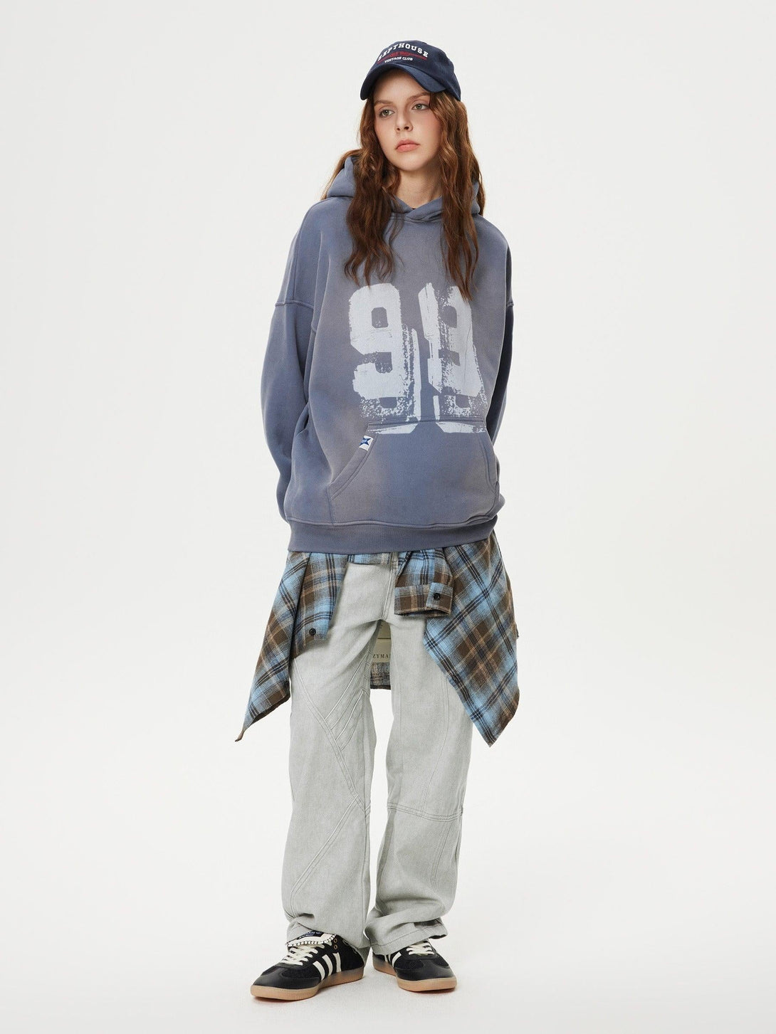 Model in TALISHKO hoodie and patchwork jeans, layered with plaid shirt for a casual look.