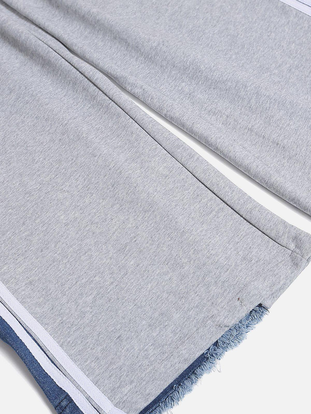 Intricate look at TALISHKO's gray sweatpants with denim patchwork and frayed hem detailing.