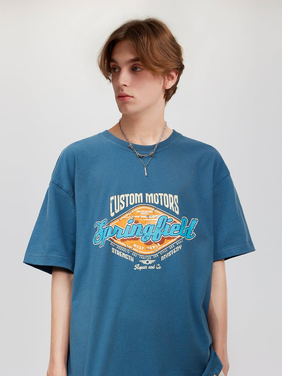 Model in a blue TALISHKO graphic tee, featuring bold lettering and casual style.
