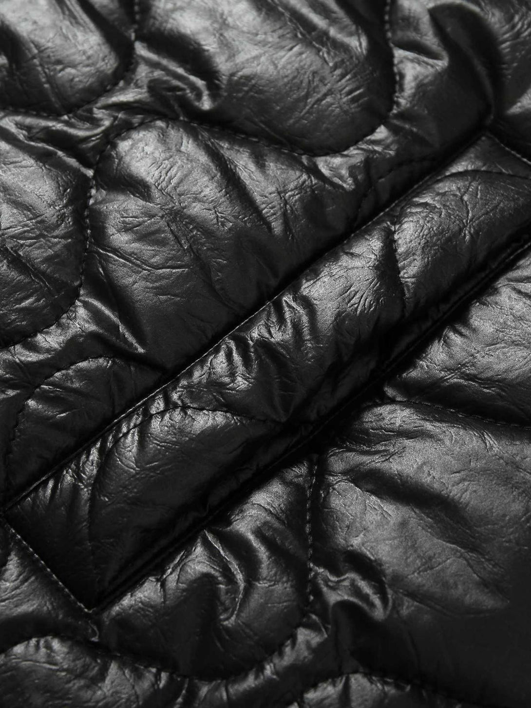 Zoomed-in texture of TALISHKO's diamond-quilted jacket, highlighting glossy fabric detail.