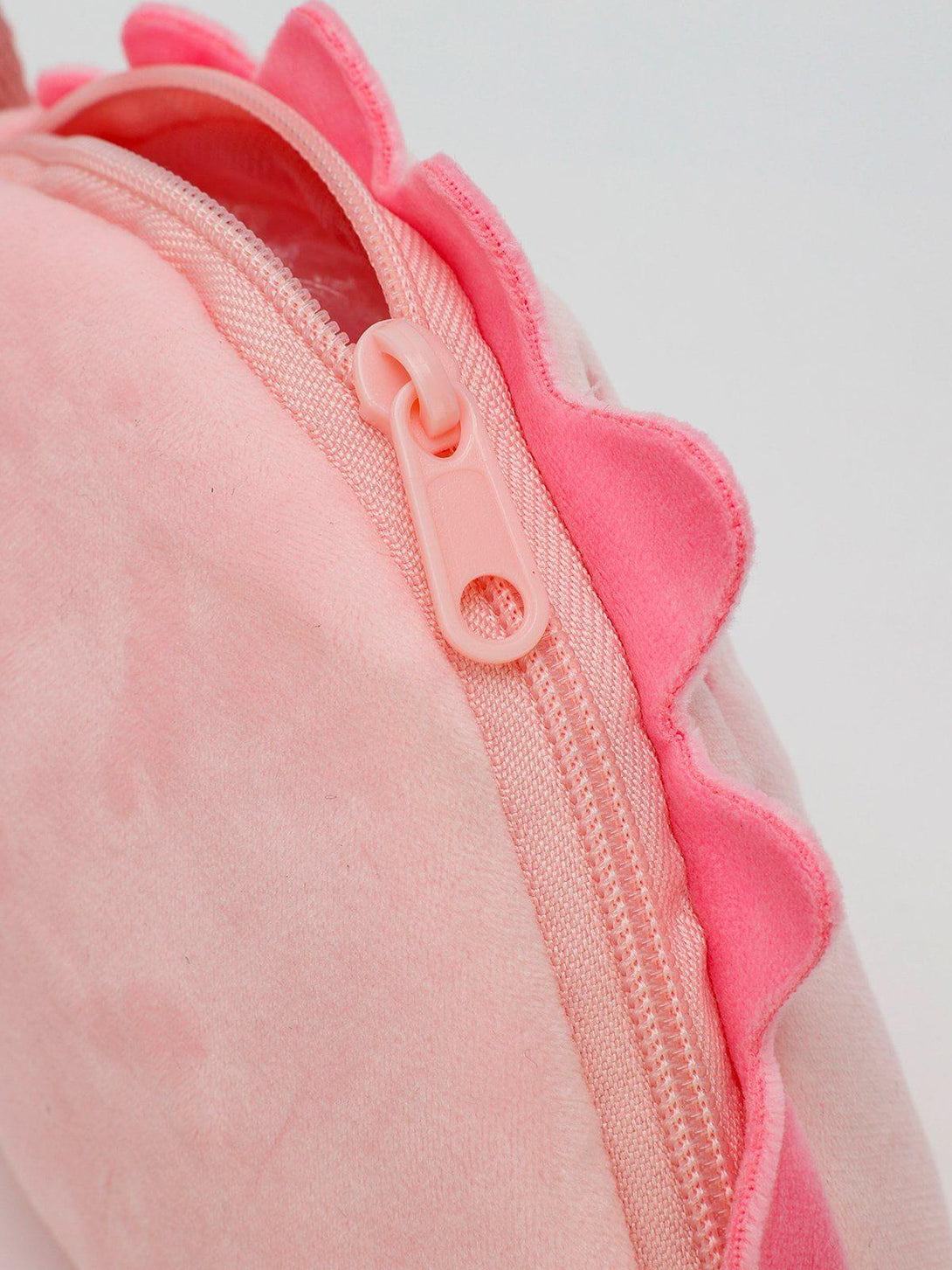 A tight crop highlighting the playful pink zipper detail on the TALISHKO dinosaur crossbody bag.