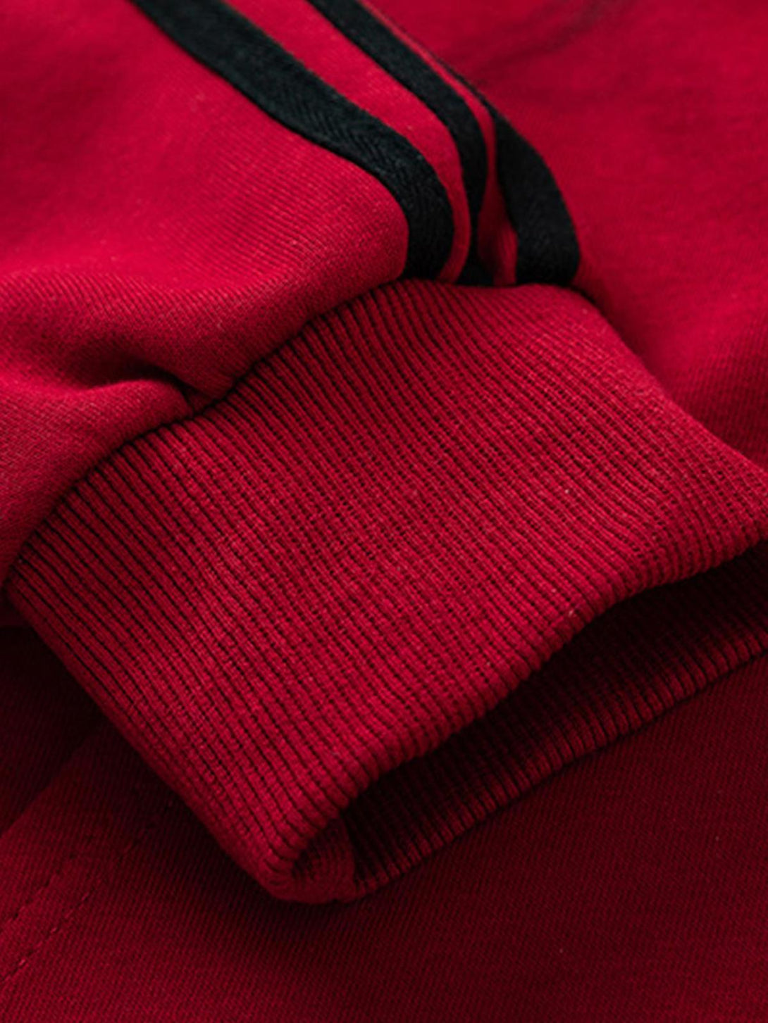 A close-up of the TALISHKO red hoodie sleeve, highlighting bold black stripe detail.