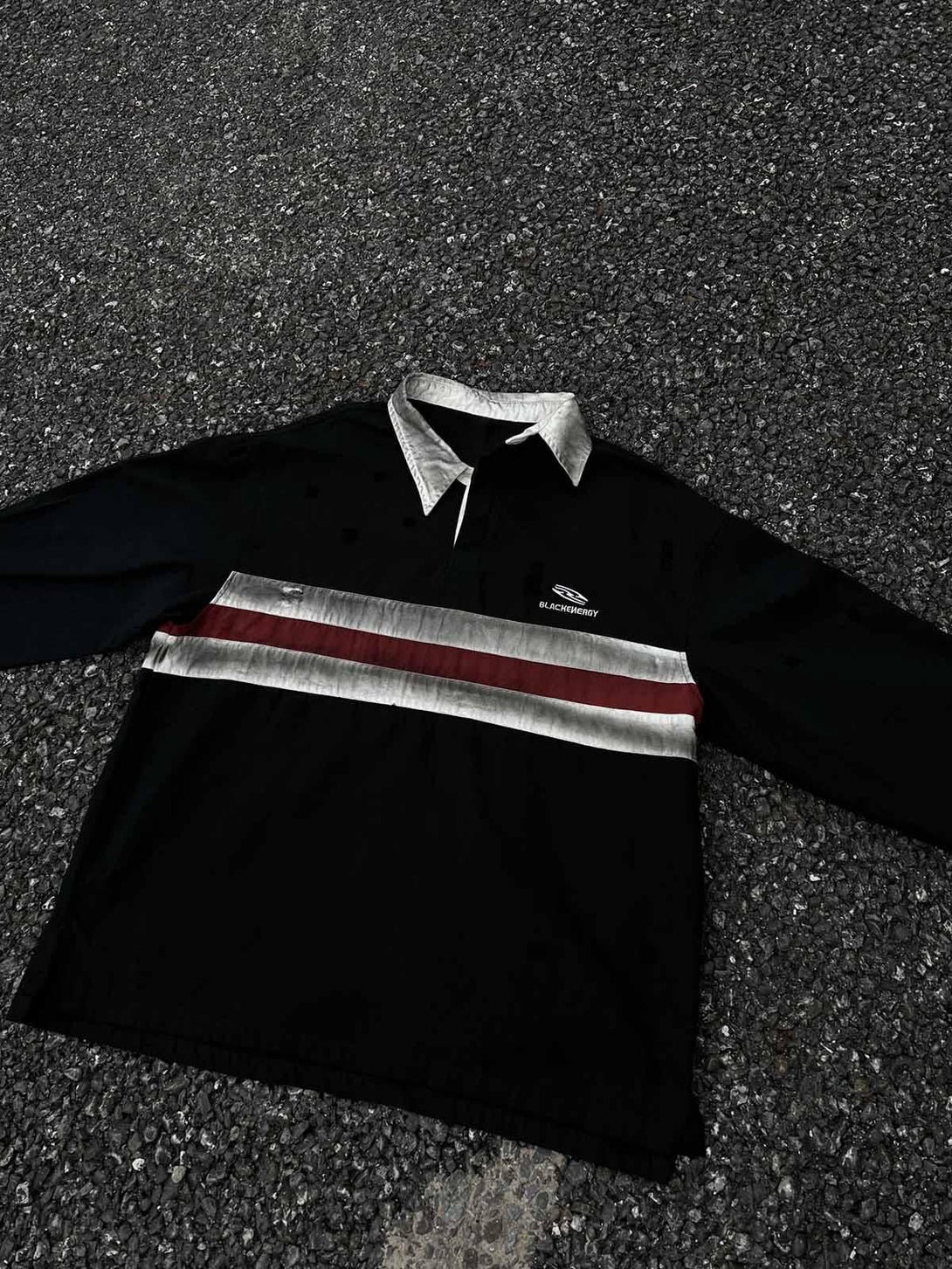 TALISHKO dirty-dye long sleeve polo with embroidered details and bold stripes on gravel.