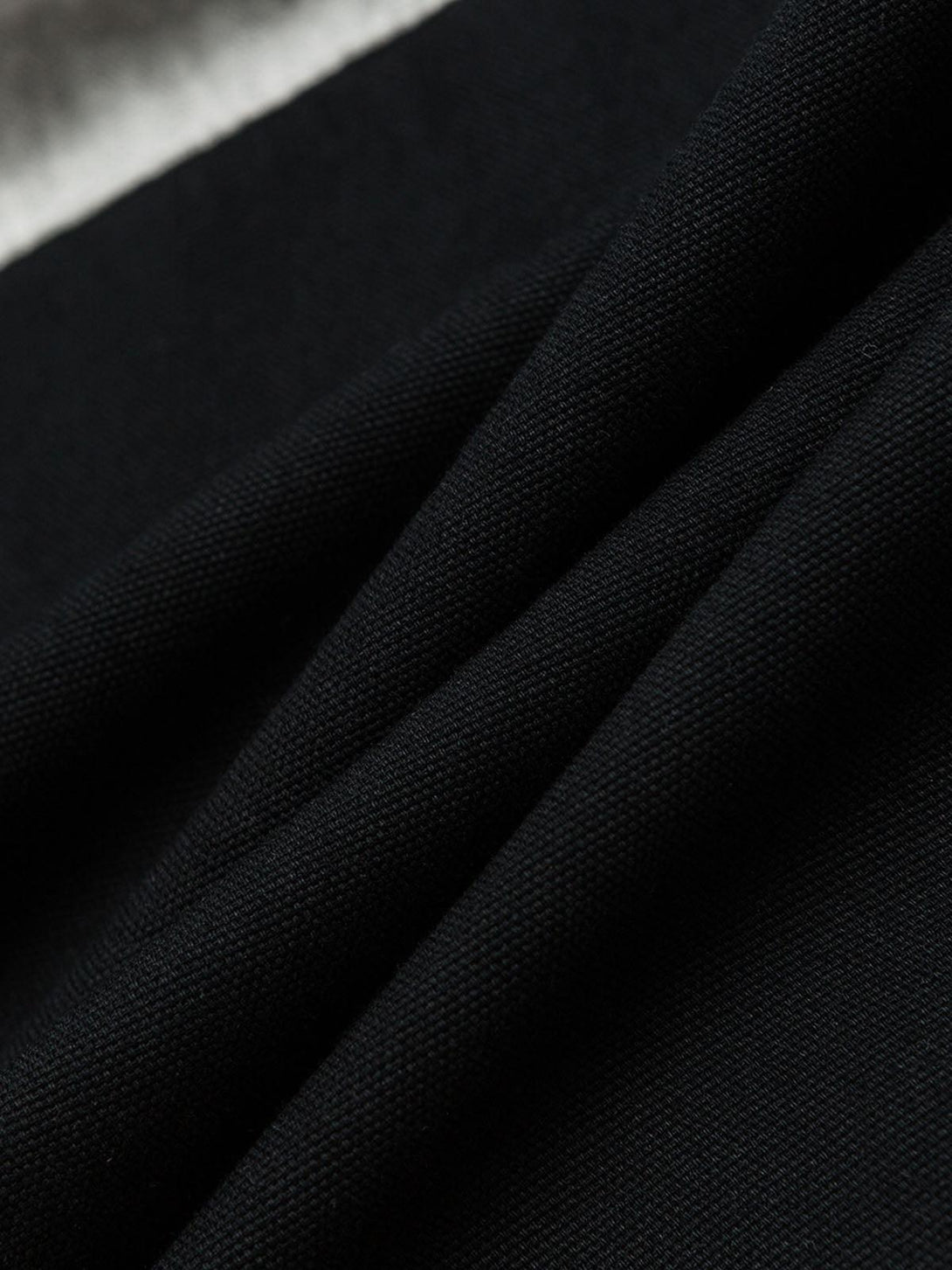 A close-up of TALISHKO's black polo fabric, highlighting the rich texture and quality.