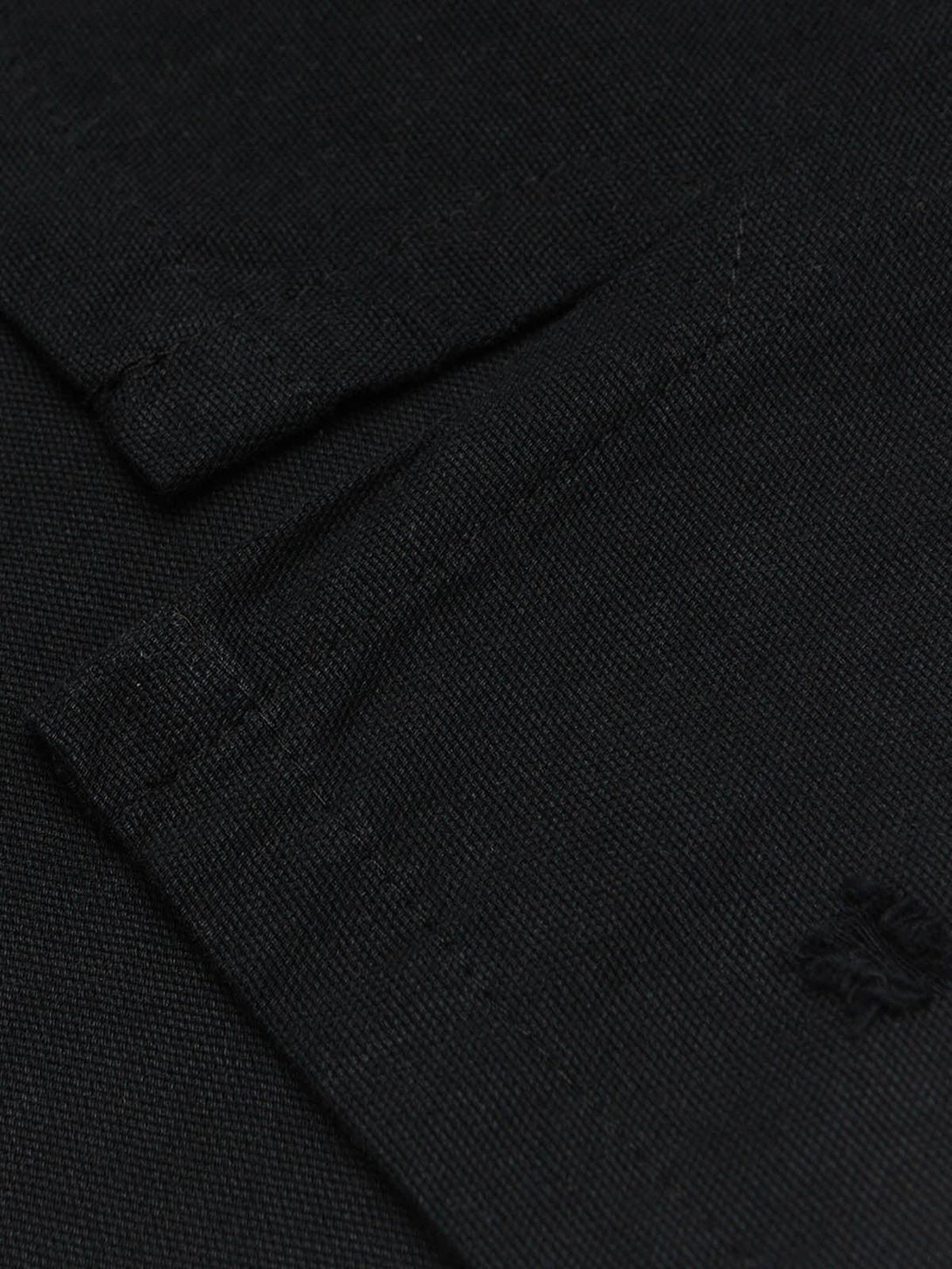 Intricate look at TALISHKO's black polo sleeve, highlighting the embroidery and texture.