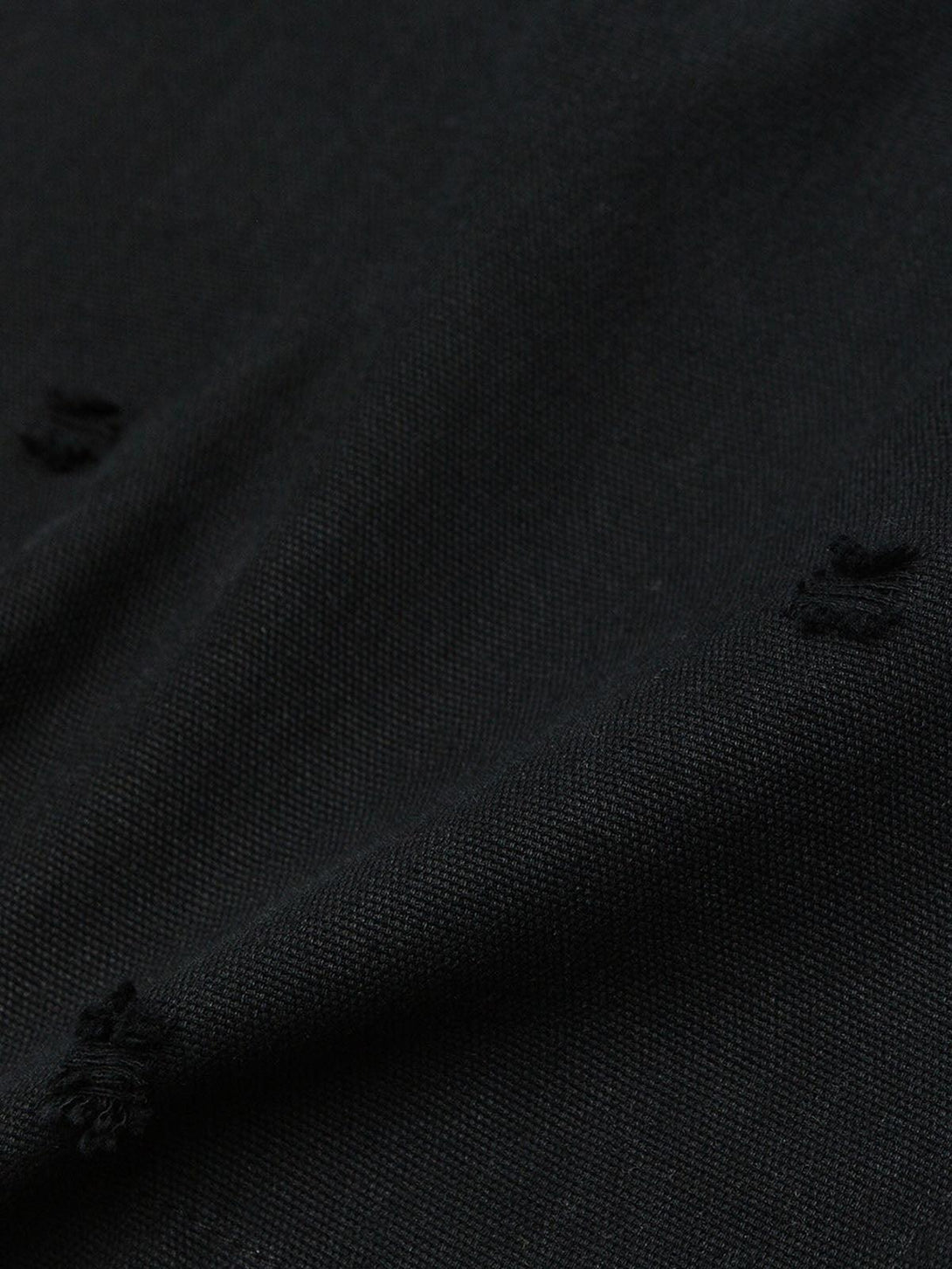 A tight crop highlighting TALISHKO's black polo fabric, showcasing detailed embroidery and texture.
