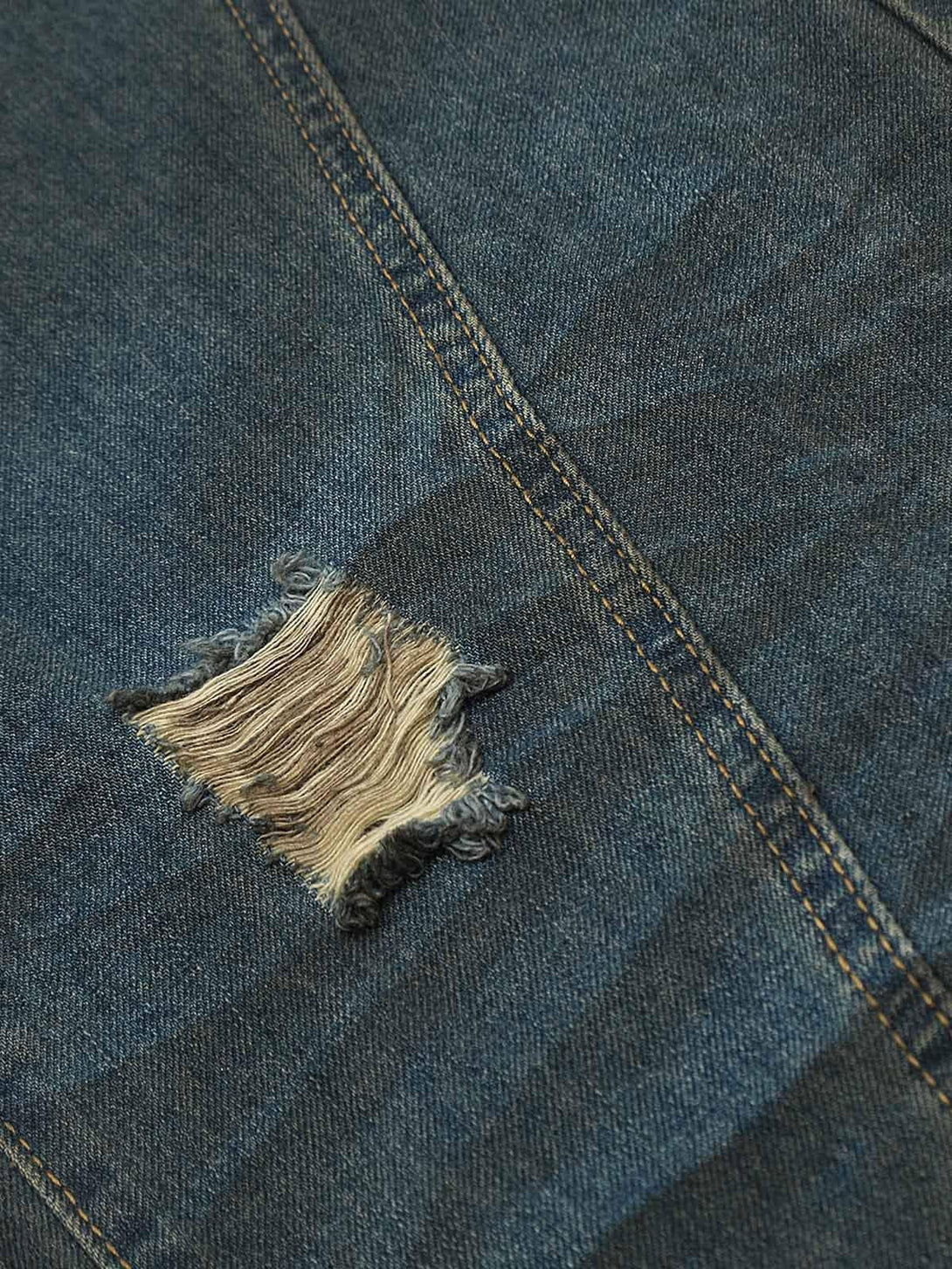 A detailed view of TALISHKO's jeans, highlighting distressed fabric and unique stitching.