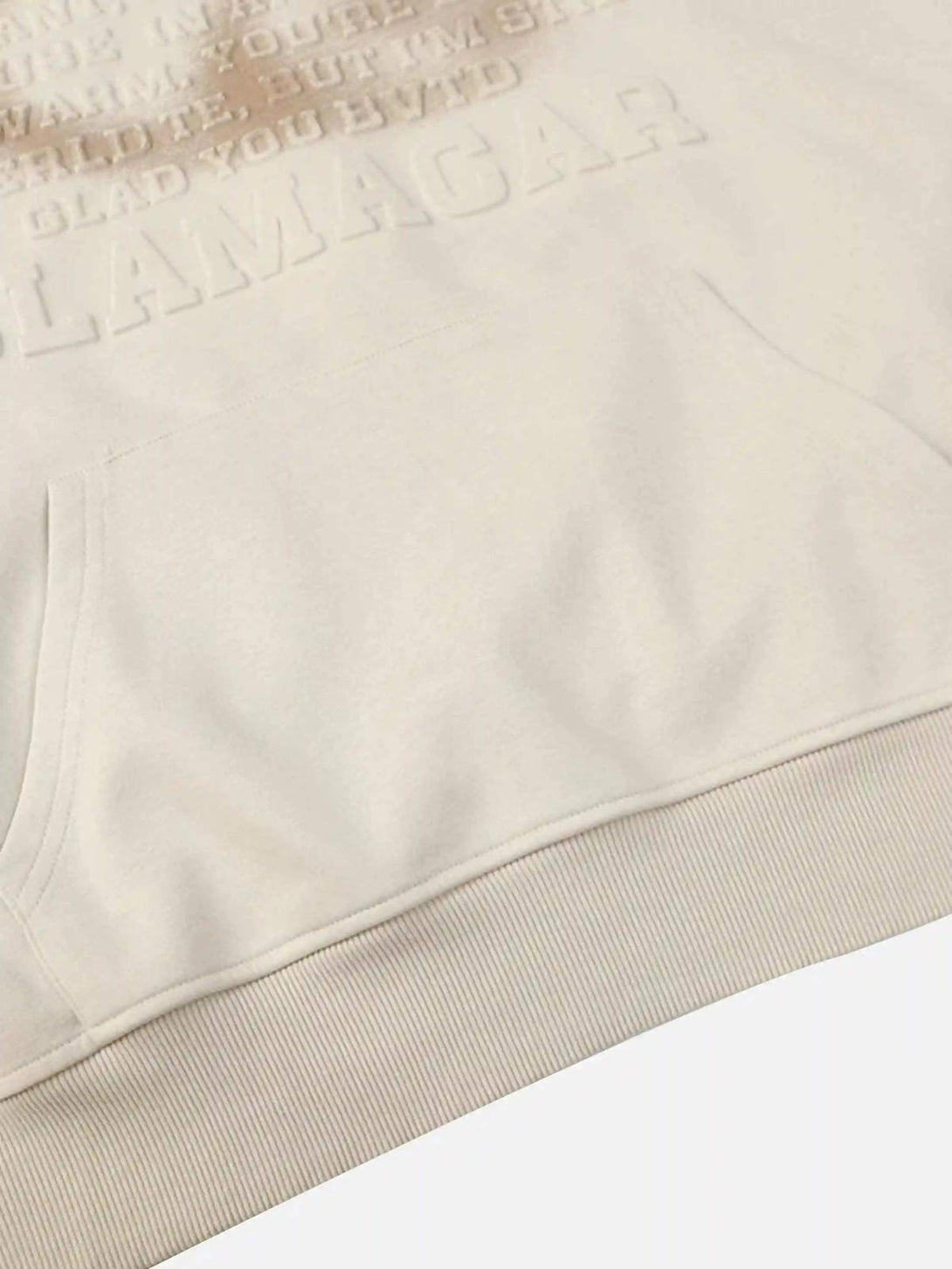 Zoomed-in detail of cream TALISHKO hoodie with embossed 3D print, showcasing texture elegance.