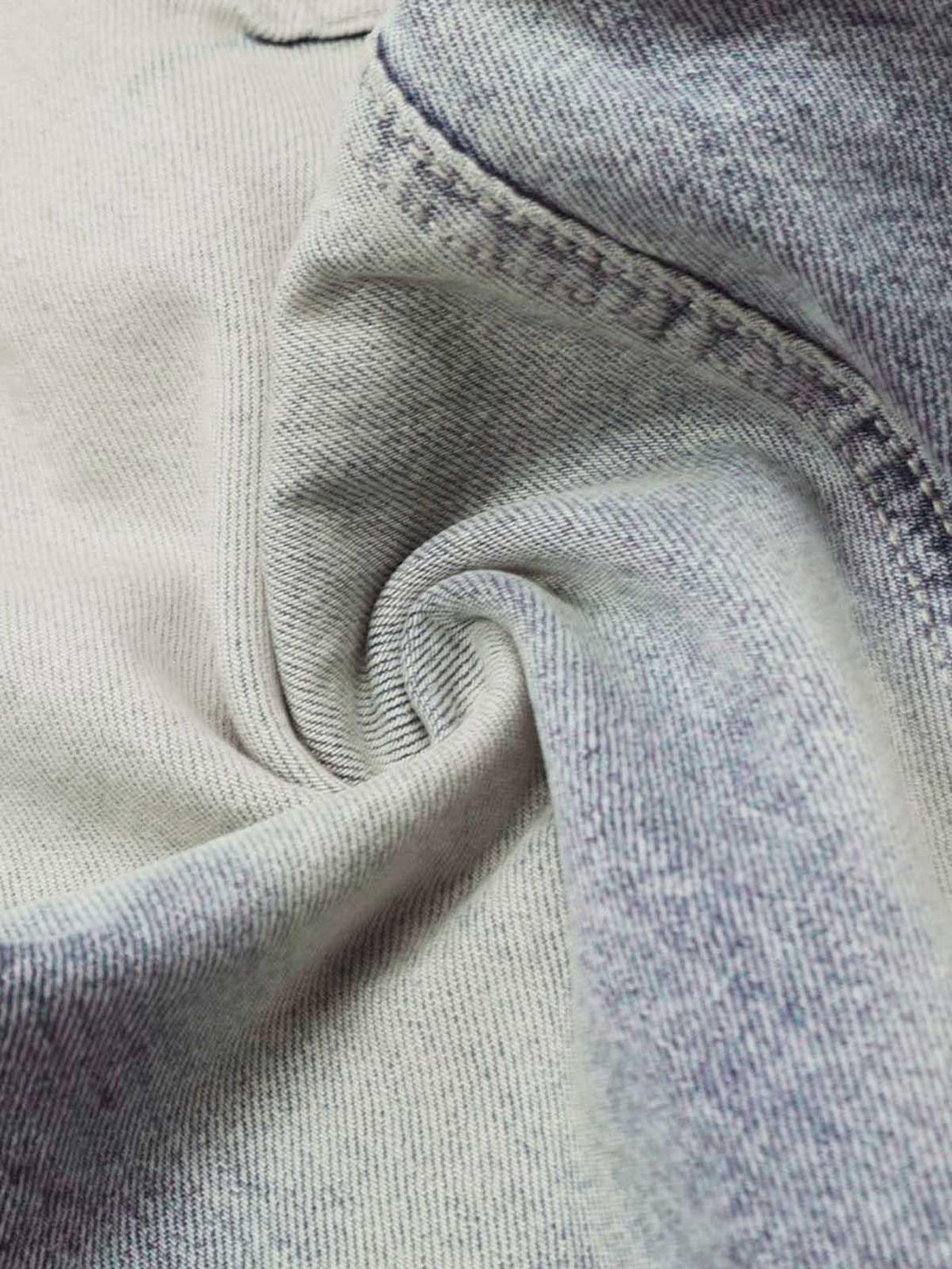 Intricate look at the denim texture of TALISHKO distressed baggy barrel jeans, emphasizing stitch detail.