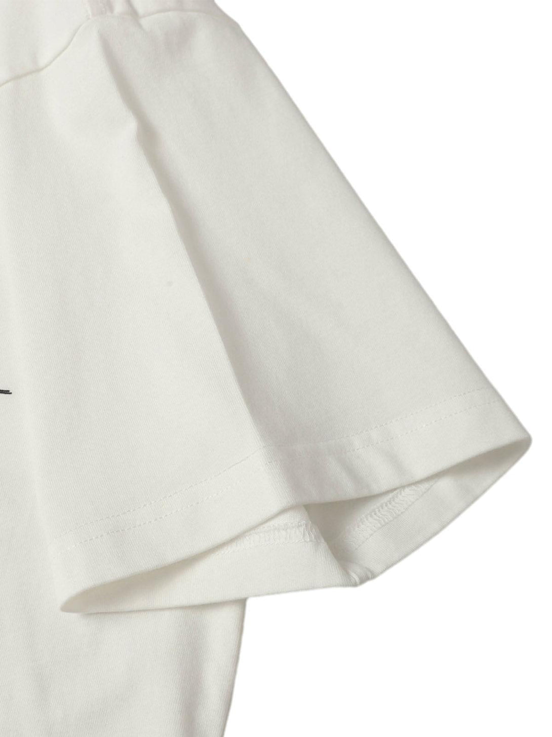 Detailed fabric and stitching of a TALISHKO distressed batik graphic T-shirt sleeve.