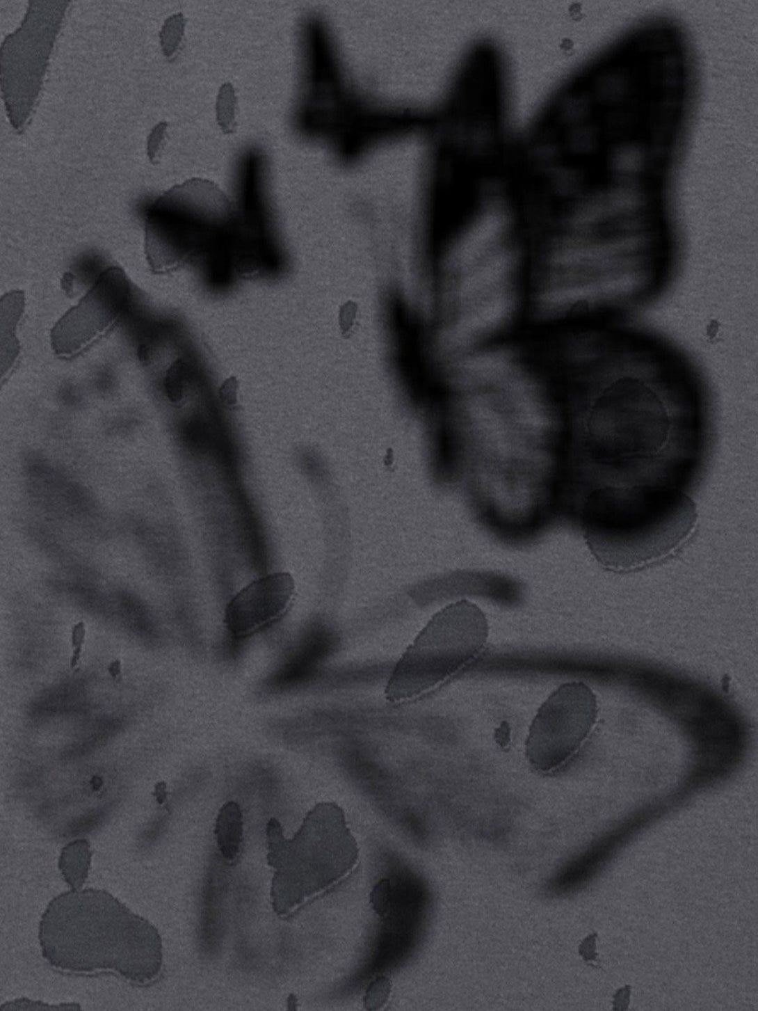 A blurred artistic view of a distressed butterfly tee by TALISHKO, highlighting unique pattern details.