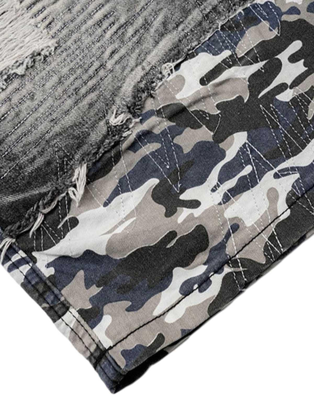 Frayed edge and camouflage pattern detail on TALISHKO distressed denim shorts, capturing a rugged style.