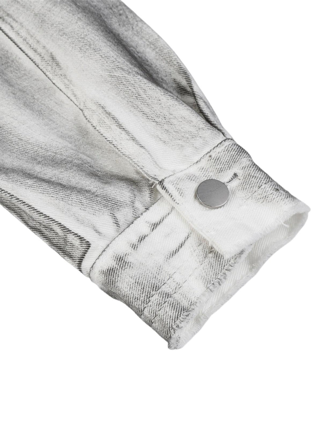 A close-up of the cuff on a distressed denim jacket by TALISHKO, featuring a metal button.