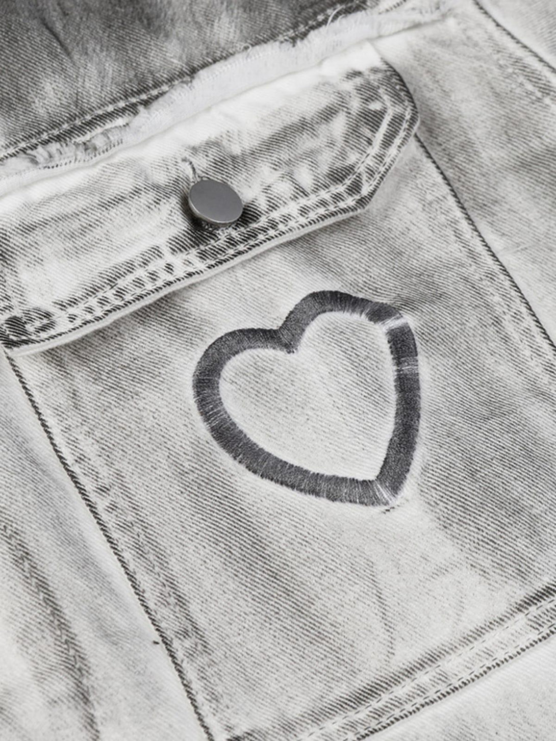 A detailed look at the heart embroidery on a distressed denim pocket by TALISHKO, adding charm.