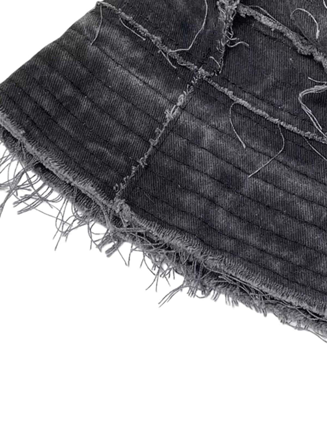A close-up of TALISHKO's distressed denim bucket hat, highlighting raw edges and frayed texture.