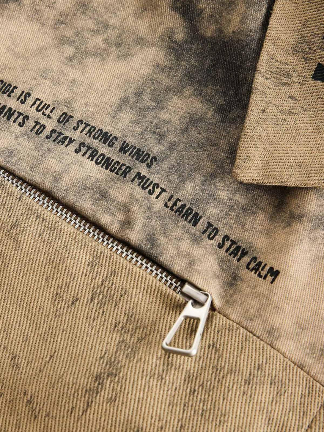 Zoomed-in texture of TALISHKO jacket highlighting distressed fabric and bold text detail.