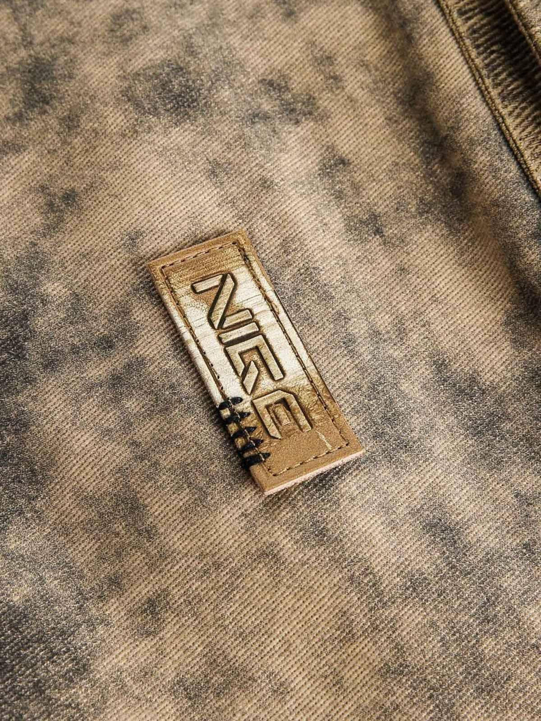 Detailed fabric and stitching of TALISHKO jacket showcasing distressed texture and bold logo.