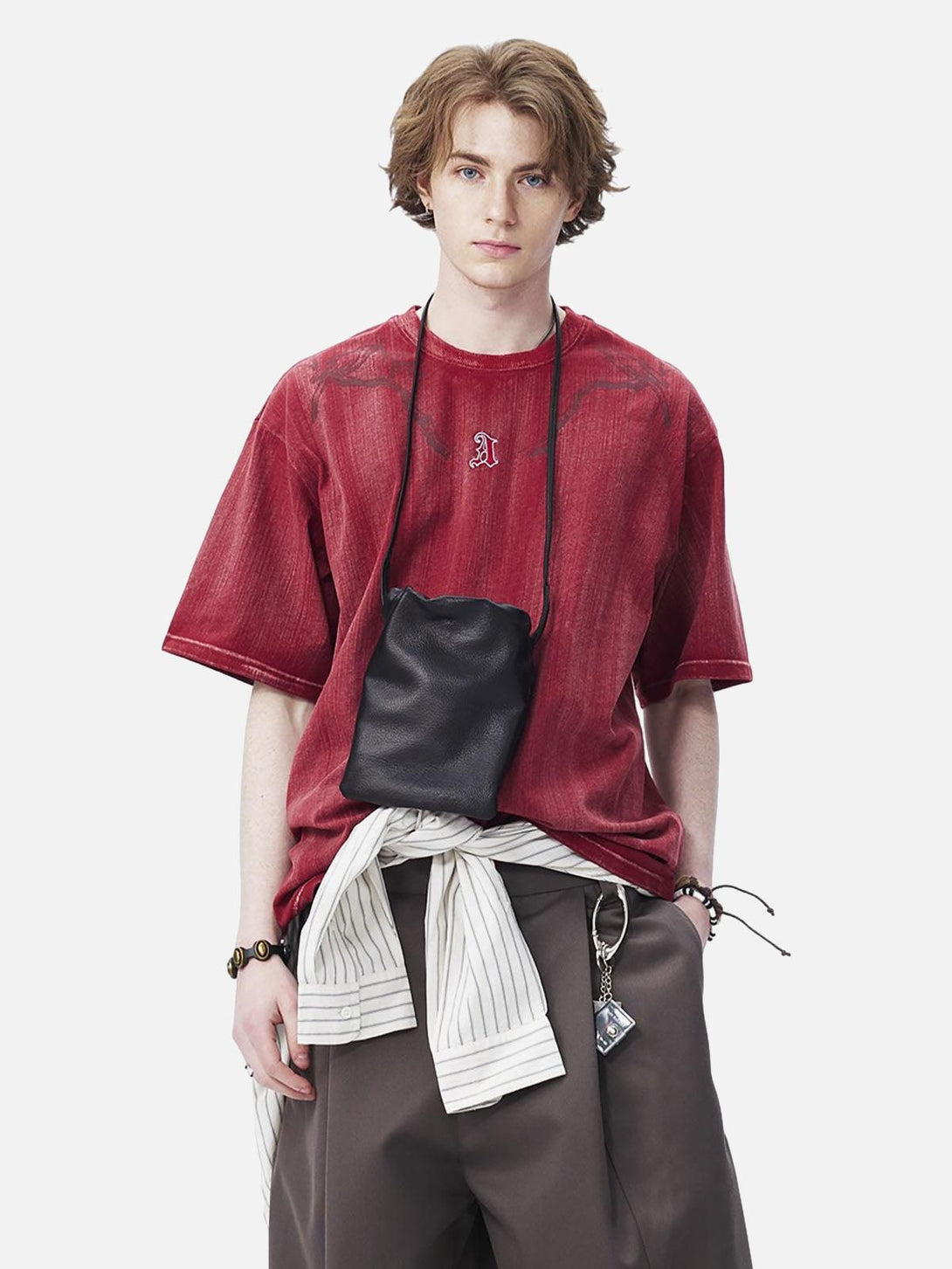 Model wearing a red distressed T-shirt with embroidery by TALISHKO, styled with layered accessories.