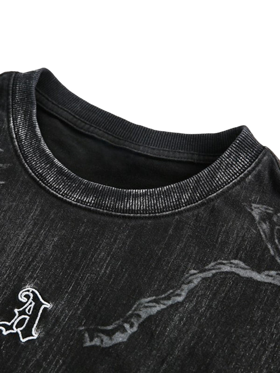 Focusing on the distressed texture and embroidery of a black TALISHKO T-shirt.