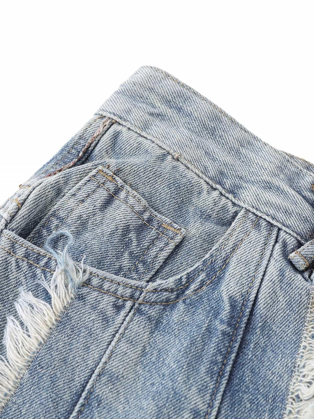 A focused view of TALISHKO's distressed jeans pocket, highlighting frayed edges and texture.
