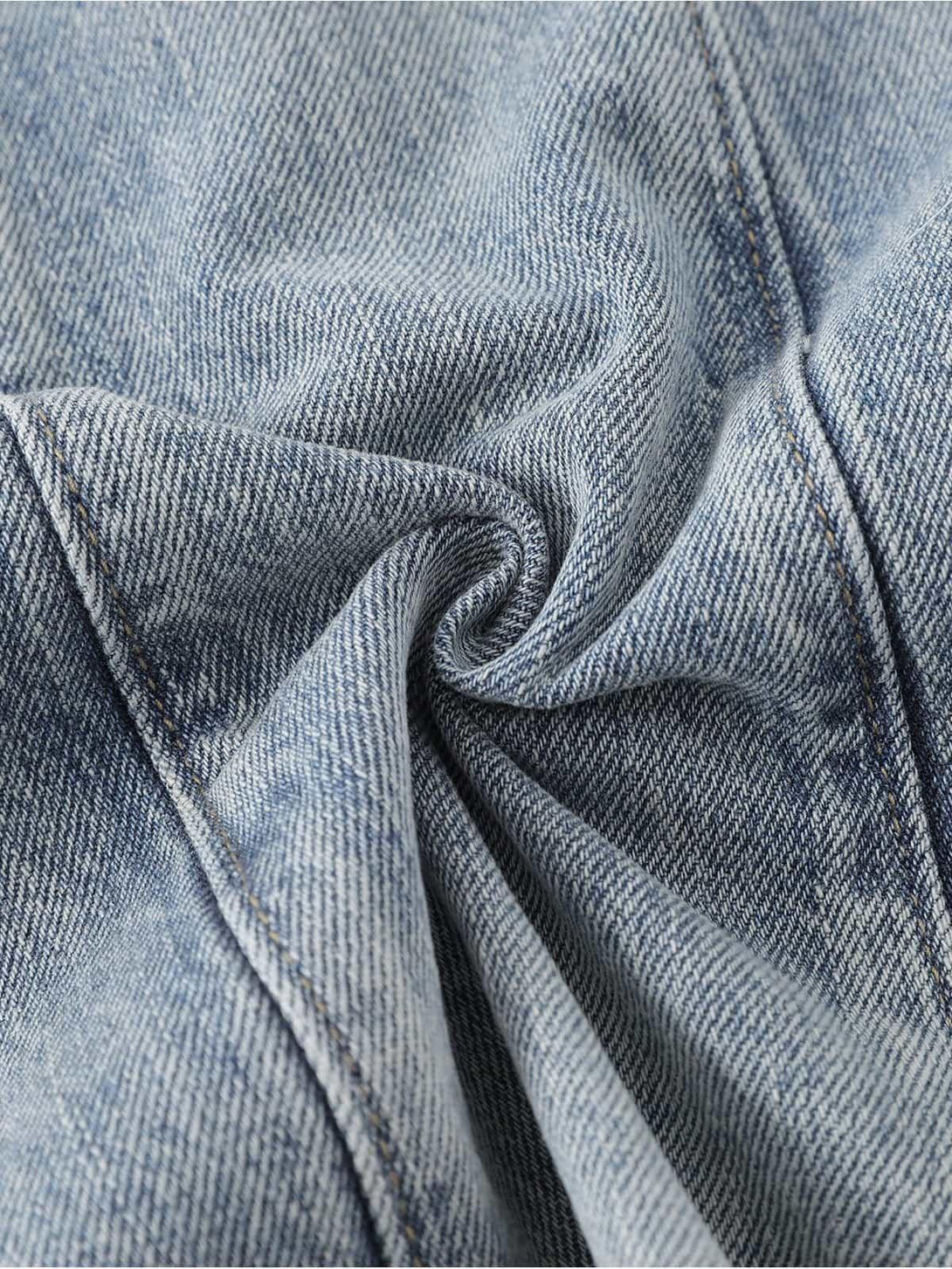 A detailed fabric and stitching view of TALISHKO's distressed baggy jeans, showing unique texture.