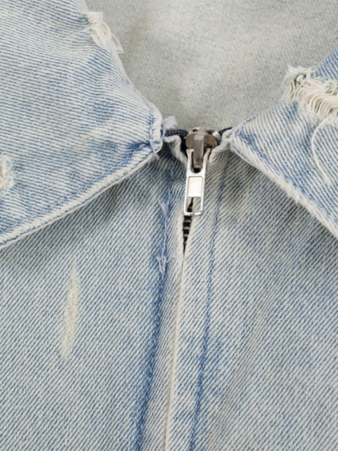 Detailed fabric and stitching of a TALISHKO denim jacket, highlighting the frayed lapel and zipper.