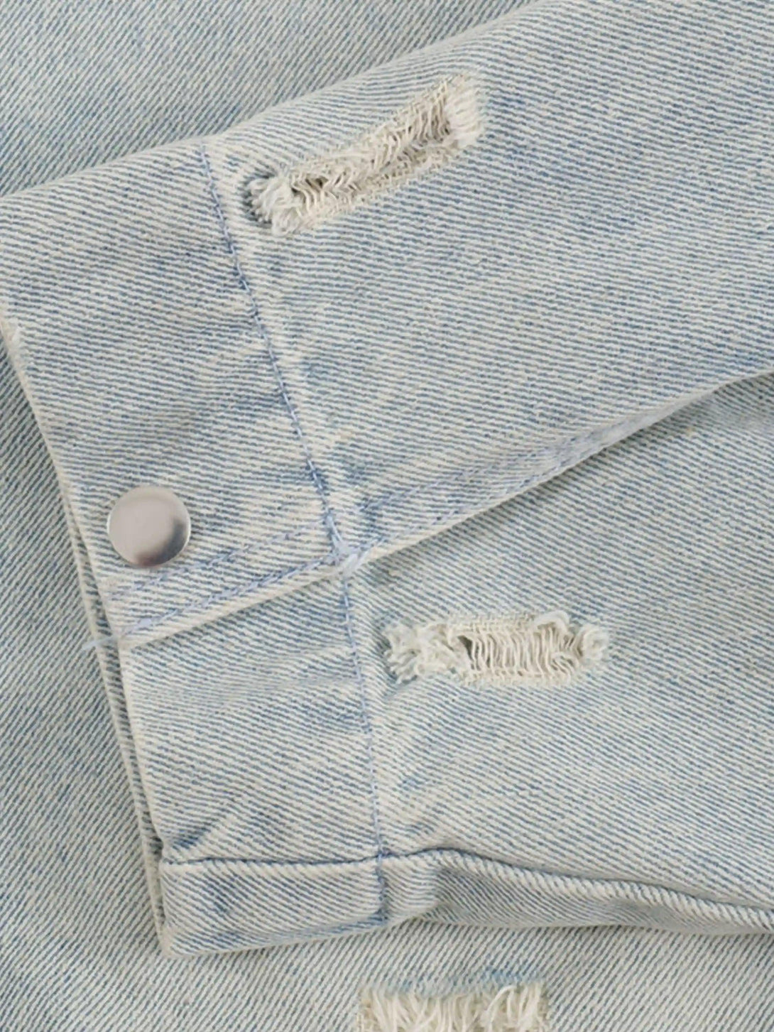 Detailed view of distressed stitching on TALISHKO denim jacket, showcasing frayed texture.