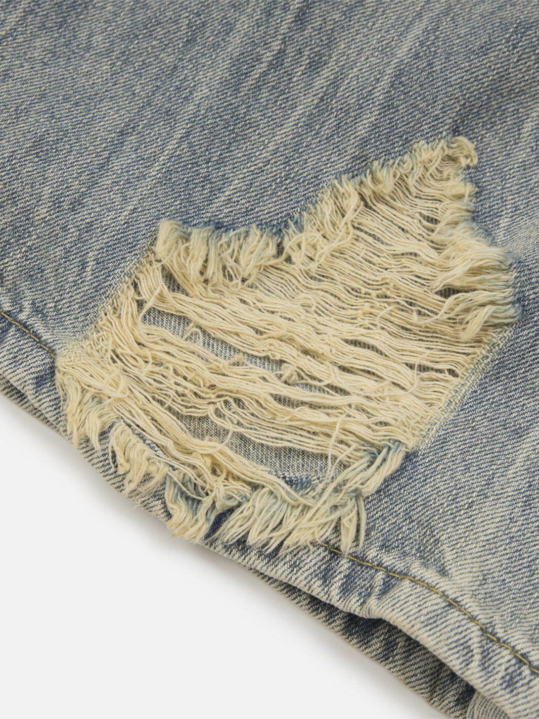 A close-up of TALISHKO distressed fringe jeans, highlighting the unique texture and frayed detail.