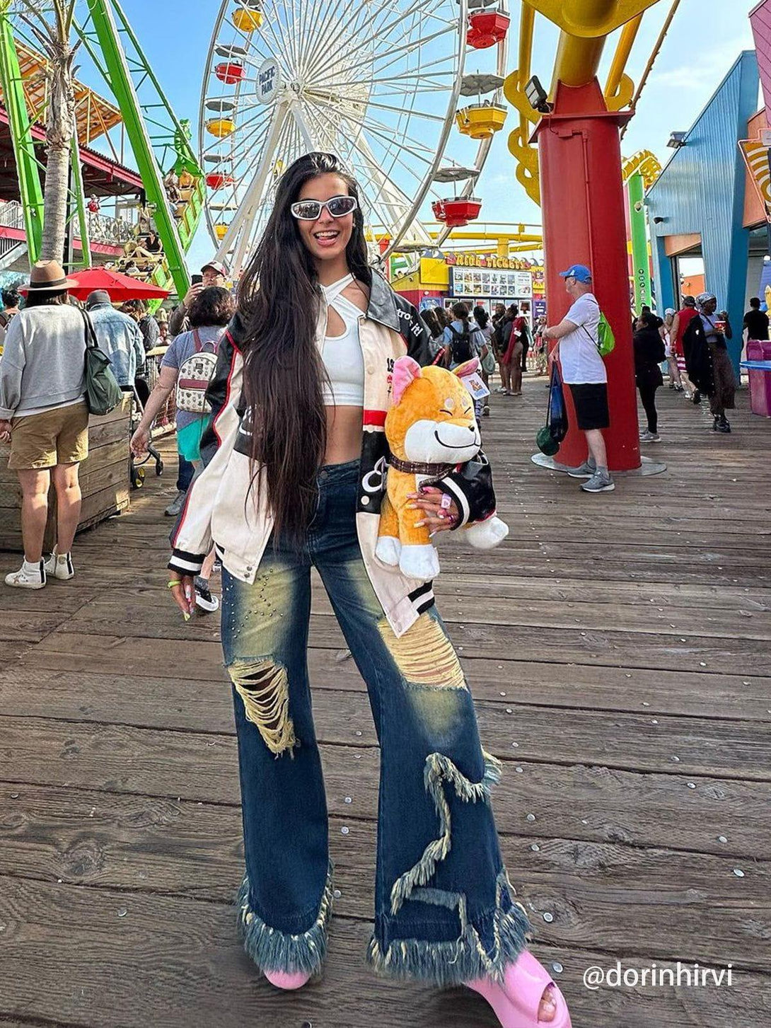Model in TALISHKO distressed fringe star jeans, enjoying a vibrant day at the amusement park.