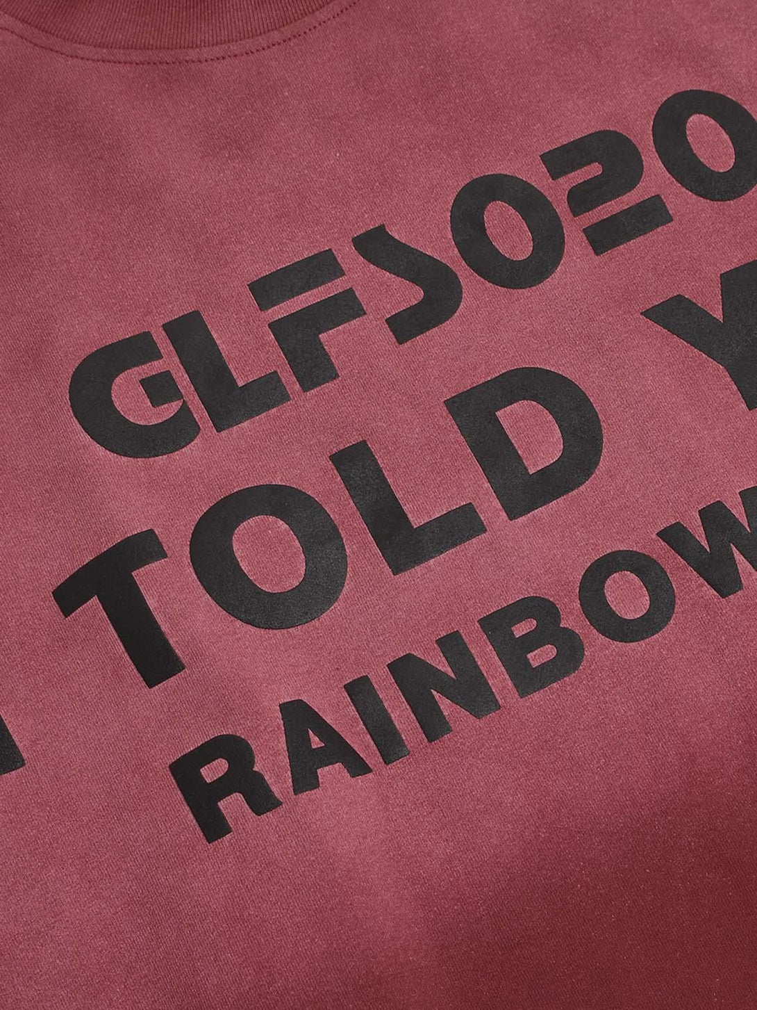 Zoomed-in view of TALISHKO T-shirt showcasing bold black lettering on a distressed red fabric.