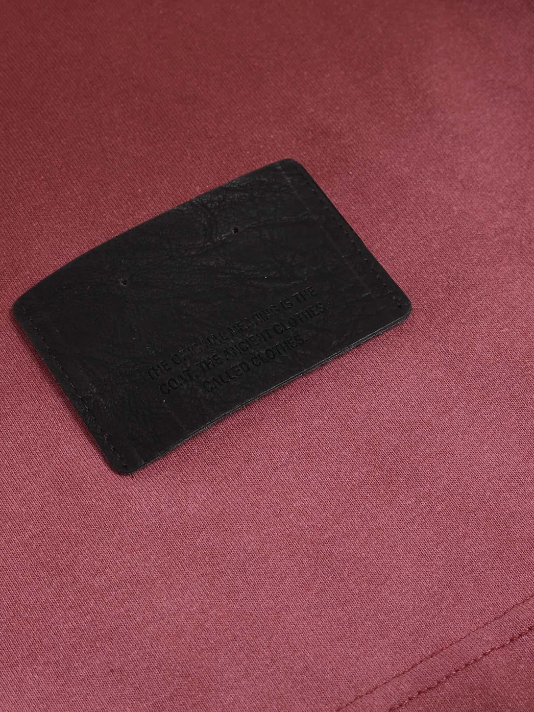 Close-up of TALISHKO T-shirt's black label on rich red fabric, highlighting texture details.