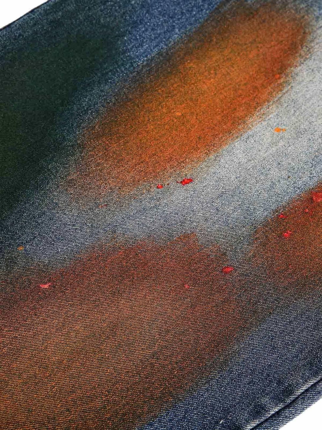 A tight crop highlighting TALISHKO jeans with vibrant graffiti-style ink details on denim.