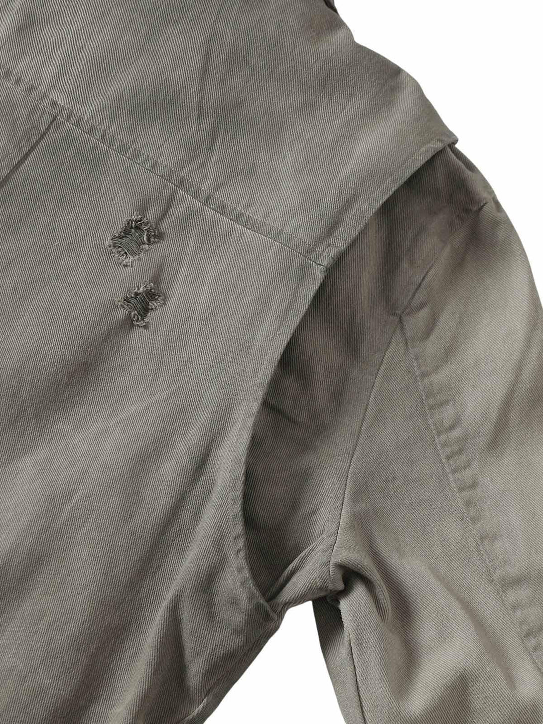 Intricate look at TALISHKO denim jacket's shoulder with distressed texture and stitching.