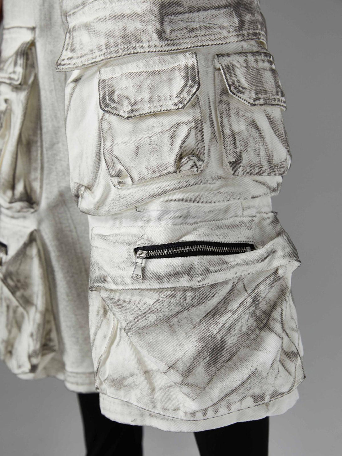 Intricate look at TALISHKO distressed cargo shorts, highlighting unique pocket and zipper detail.