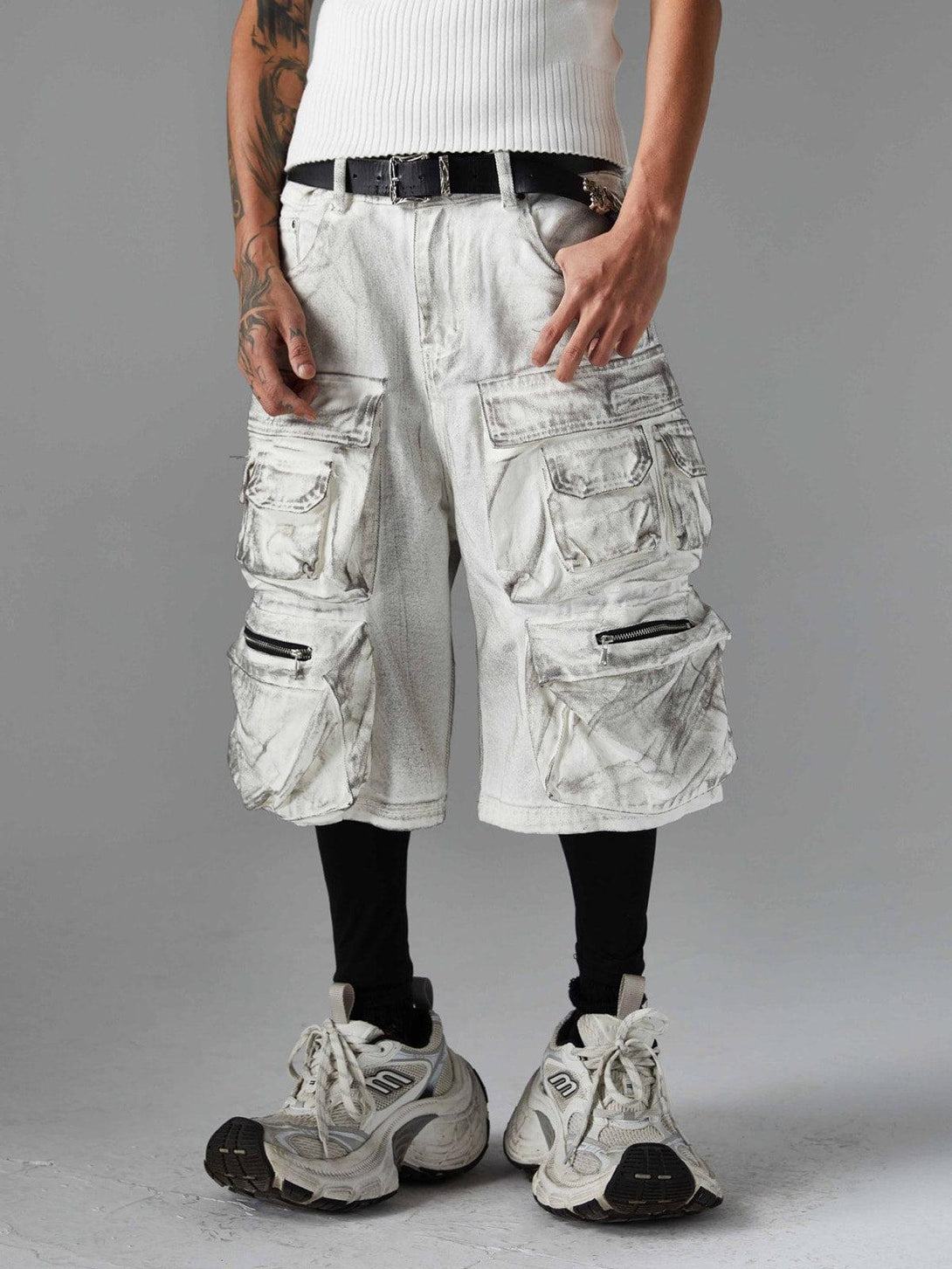 Model wearing TALISHKO distressed cargo shorts with multiple pockets, paired with chunky sneakers.