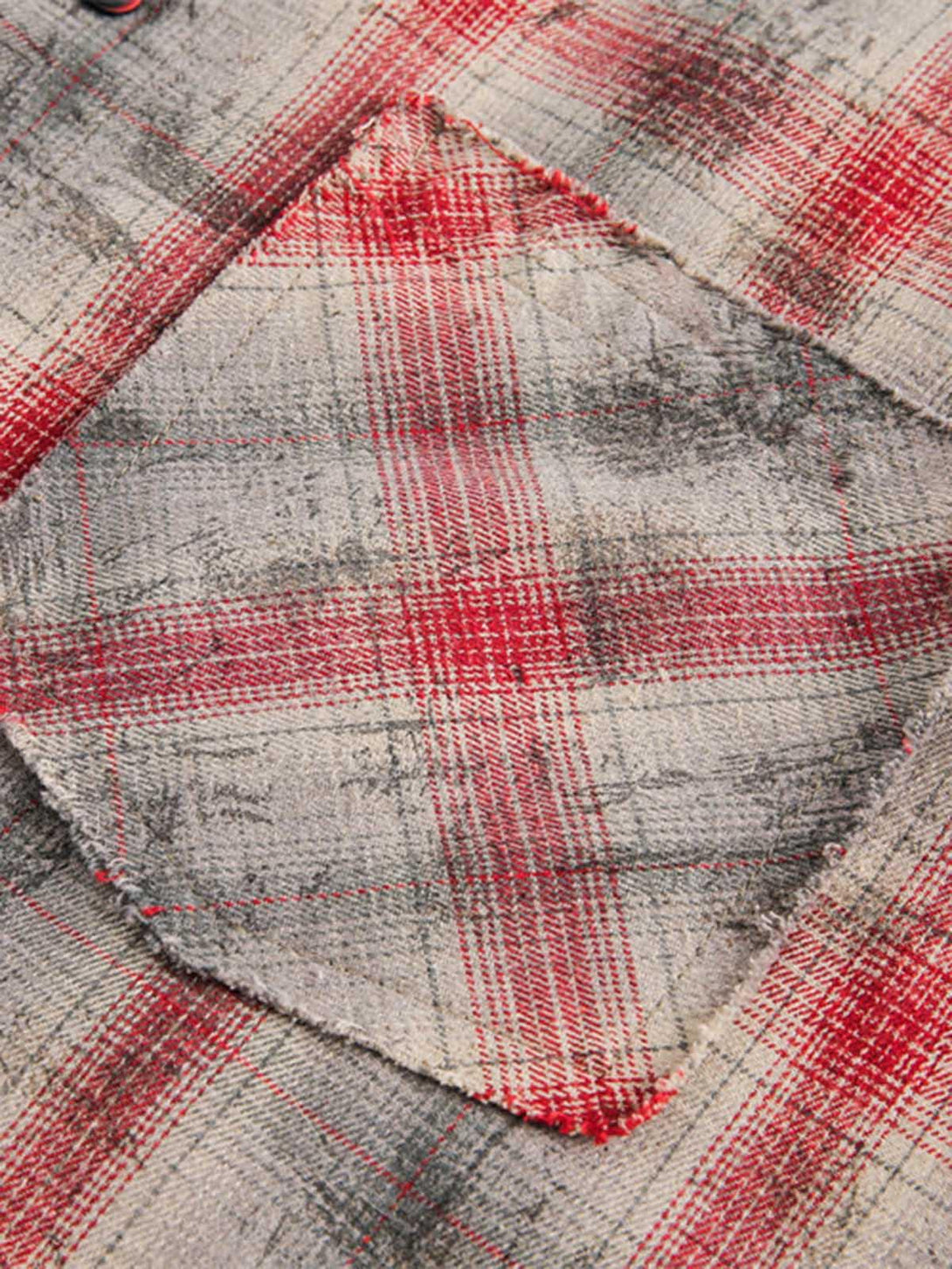 Zoomed-in texture of the distressed plaid fabric and pocket detail on a TALISHKO shirt.