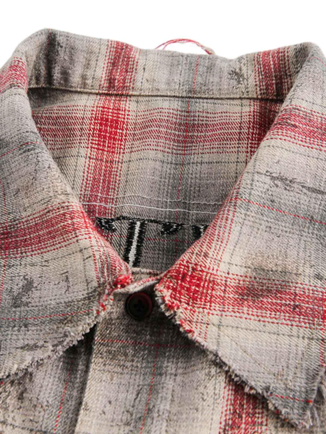 Intricate look at the distressed plaid fabric and stitching of a short-sleeve shirt by TALISHKO.