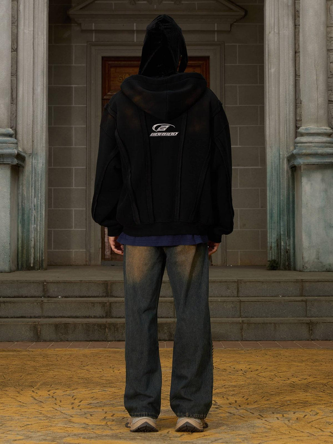 Rear view of a TALISHKO distressed patchwork velvet jacket, paired with relaxed denim jeans.