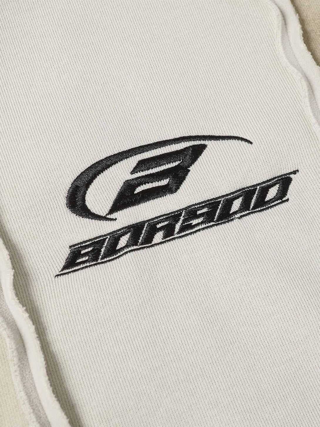 Detailed look at TALISHKO logo stitching on distressed patchwork velvet jacket.