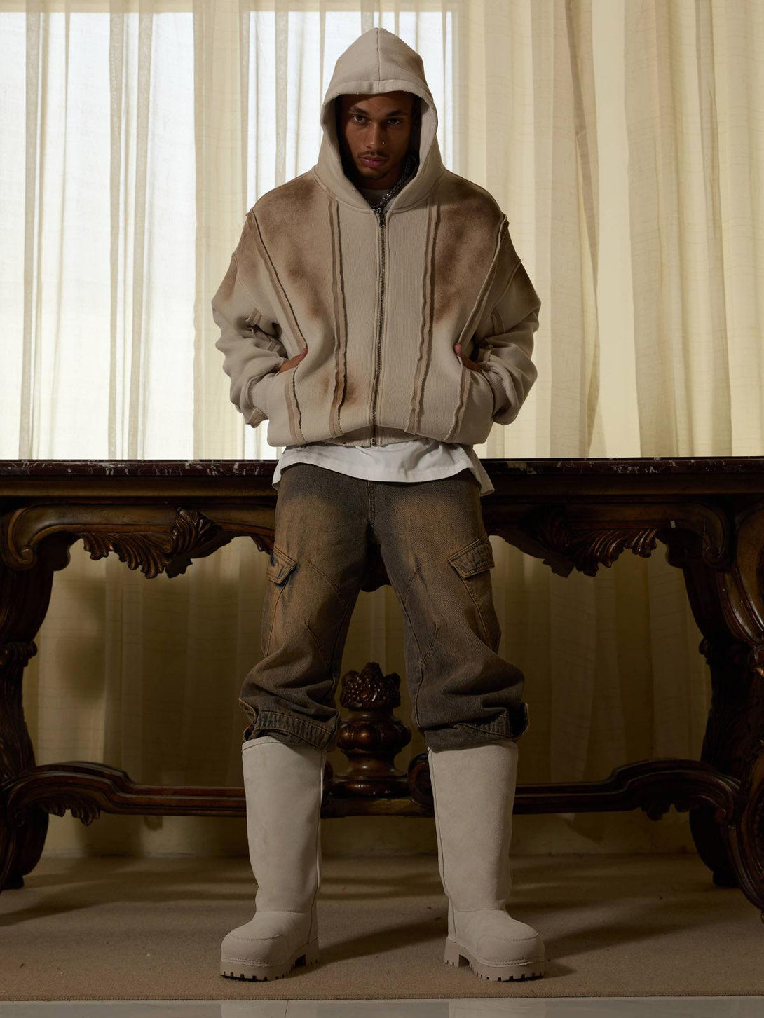 Model wearing a TALISHKO distressed patchwork velvet jacket, paired with rugged pants and boots.