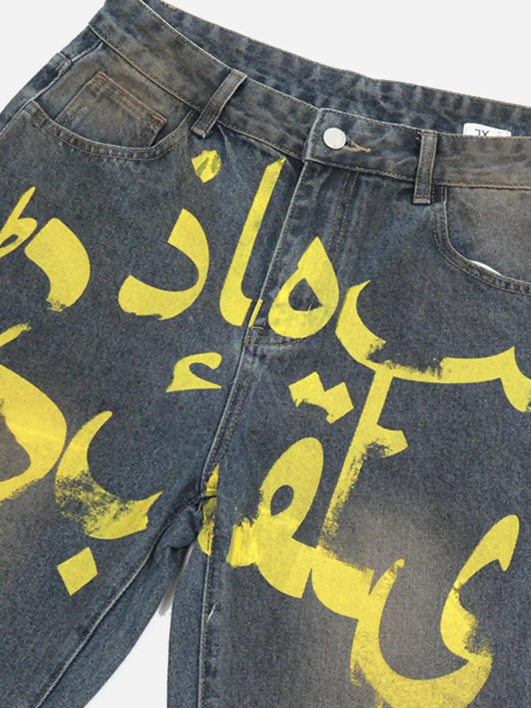A detailed view of TALISHKO bootcut jeans with vibrant yellow graphic print and distressed finish.