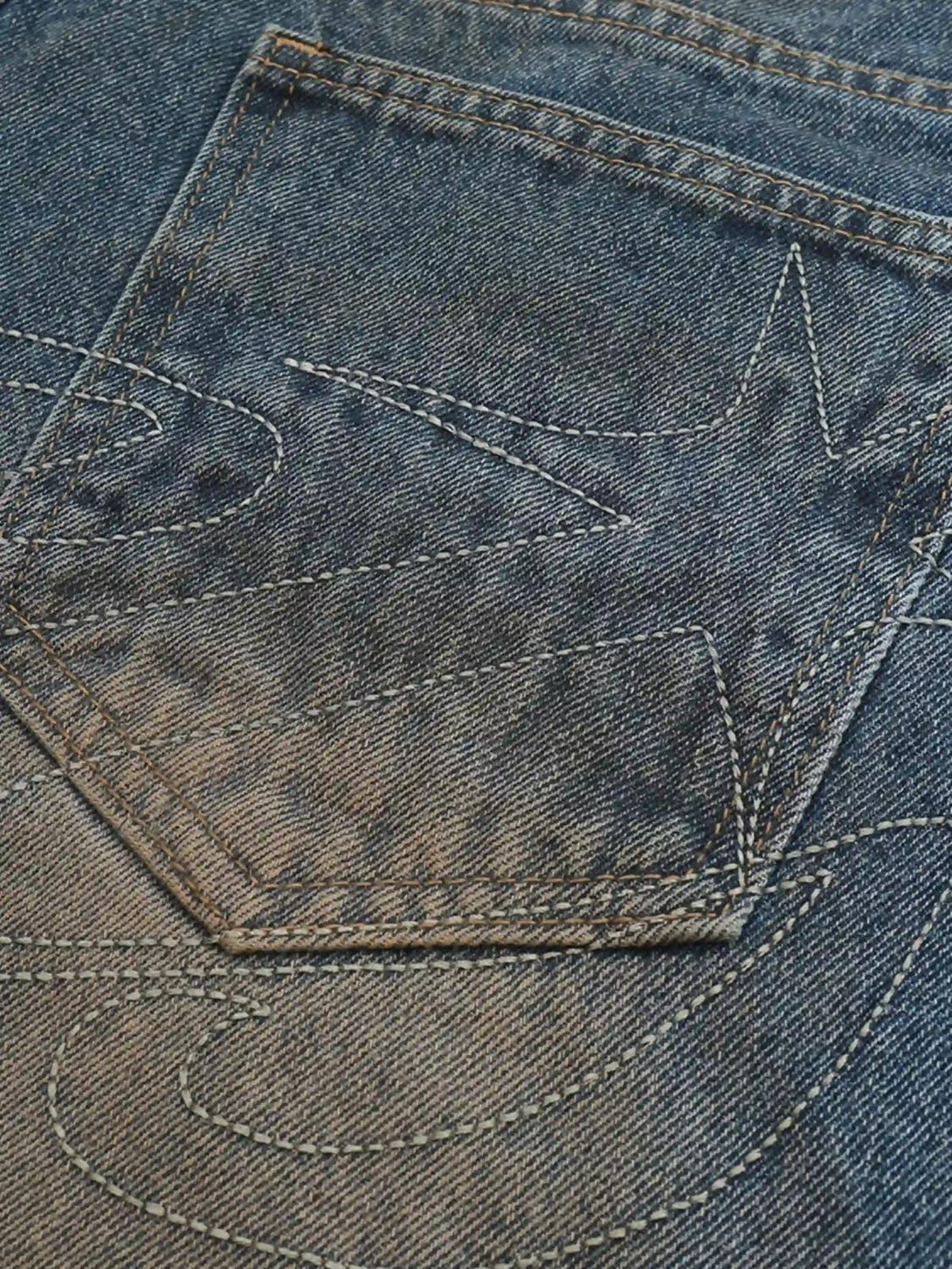 Intricate stitching detail on TALISHKO bootcut jeans, highlighting the unique pigment pattern.