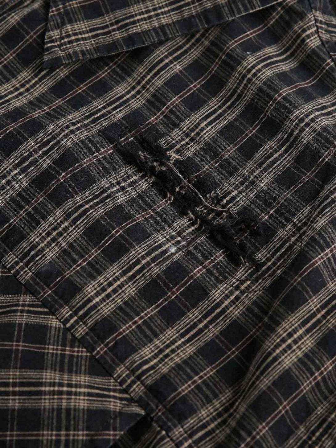 Focusing on the distressed detail of a plaid shirt by TALISHKO, highlighting unique texture.