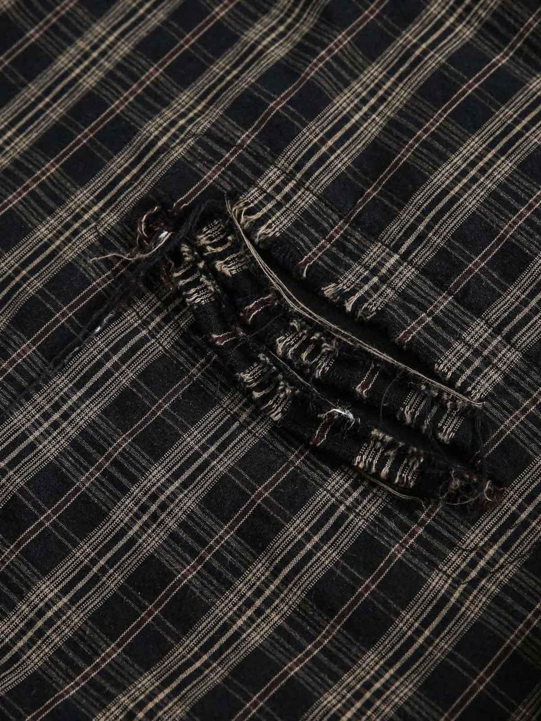 Zoomed-in texture of the distressed plaid pattern and pocket detail on a TALISHKO shirt.