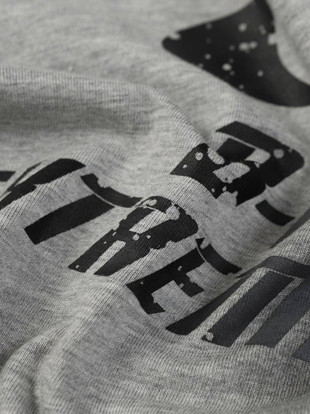 A detailed look at TALISHKO's gray T-shirt, showcasing its distressed graphic design.